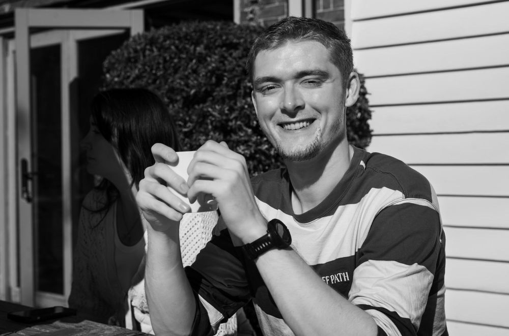 Jamie smiling in the sun with a cup
