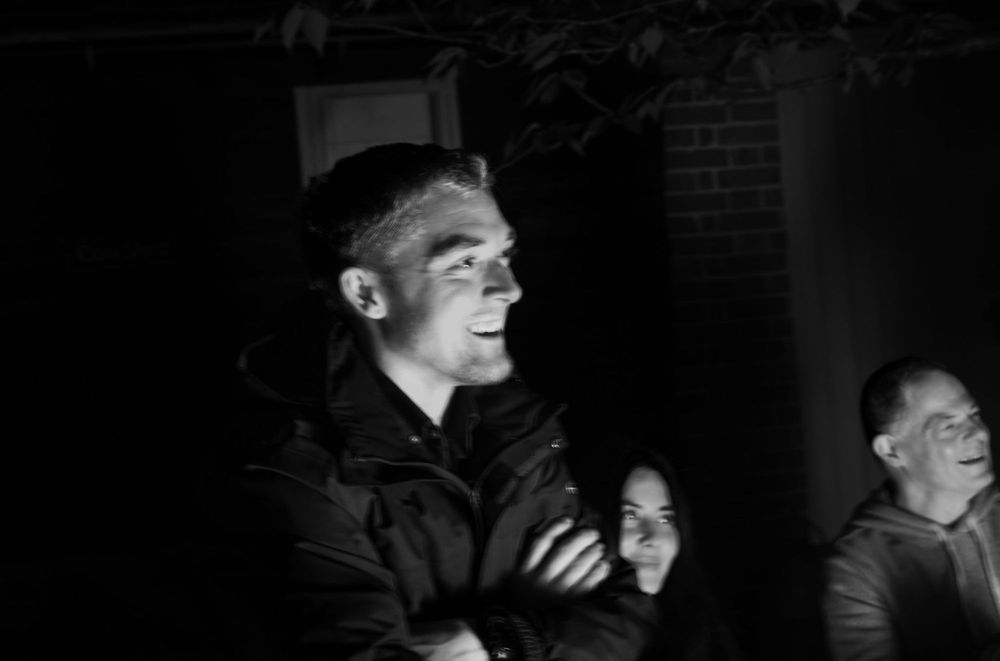 Jamie laughing by a fire at night